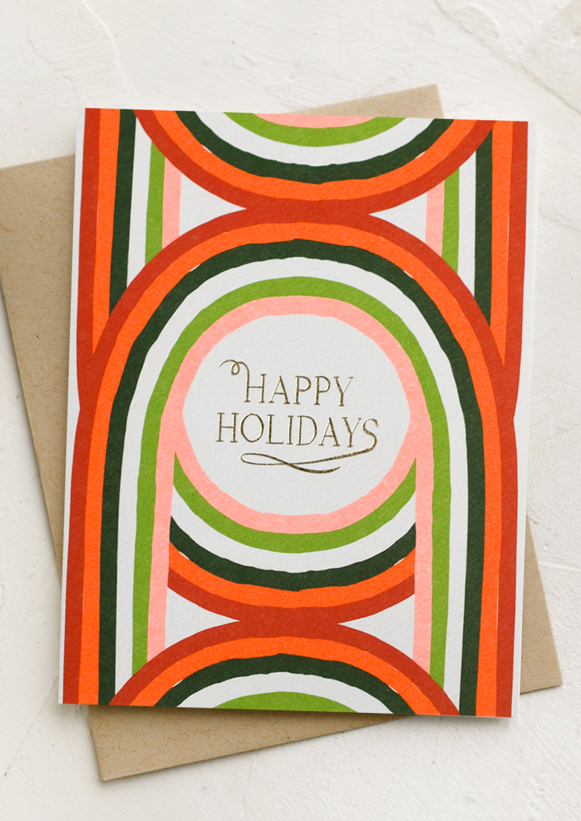 A holiday card with geometric arch print in red and green, text reads "happy holidays".