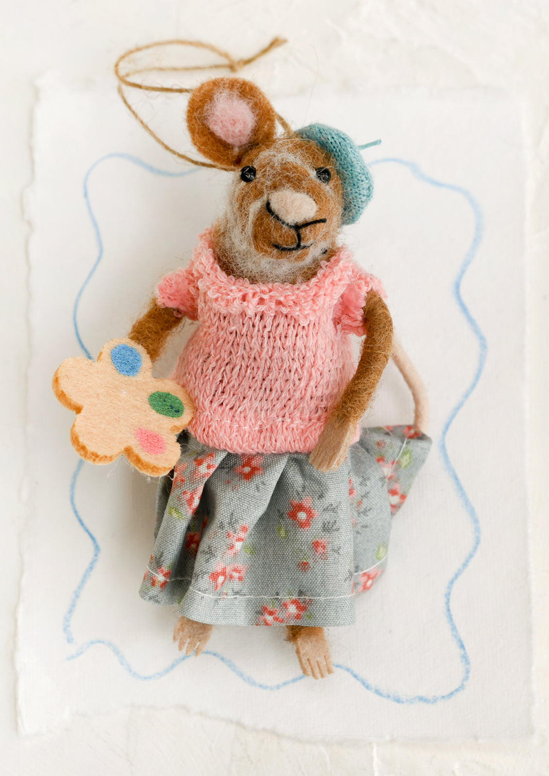 A felted mouse ornament wearing beret and holding palette.