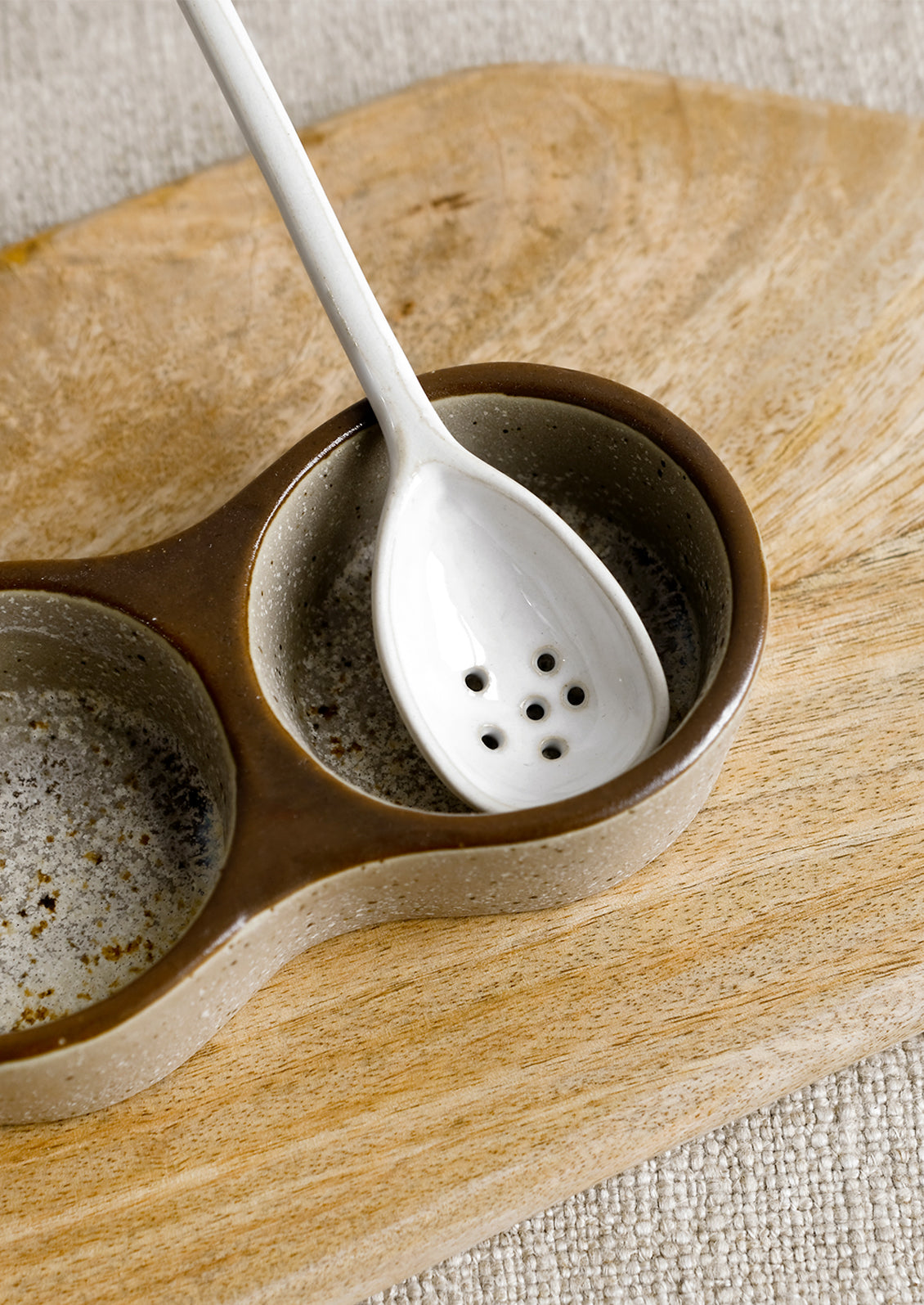 A small slotted white ceramic spoon.
