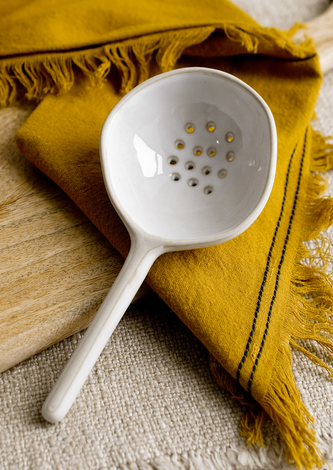A large slotted white ceramic spoon.