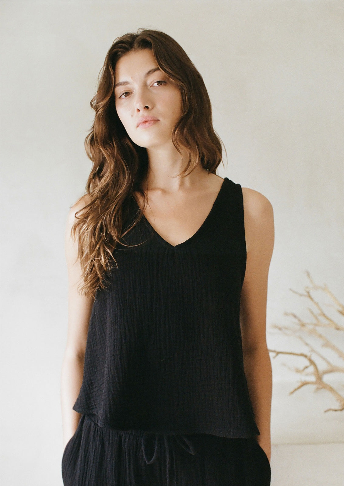 A woman in a black cotton gauze v-neck tank top. 