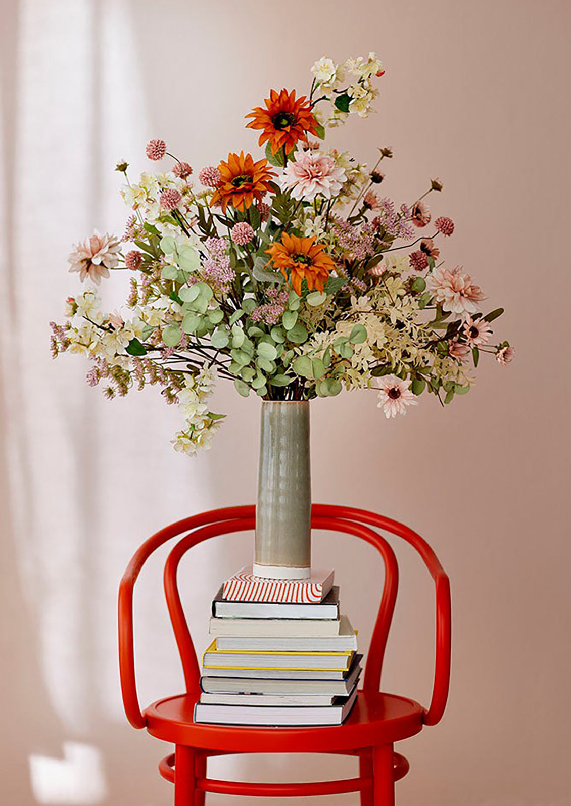 A faux flower arrangement with pink flowers and orange sunflowers.