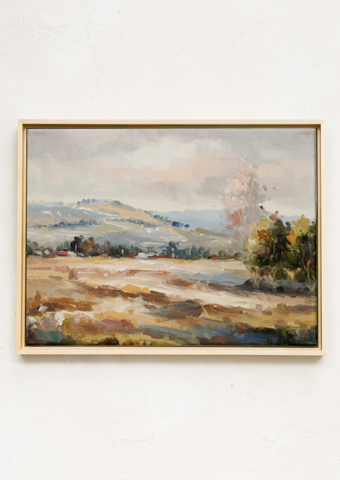 A framed landscape oil painting in muted fall tones.