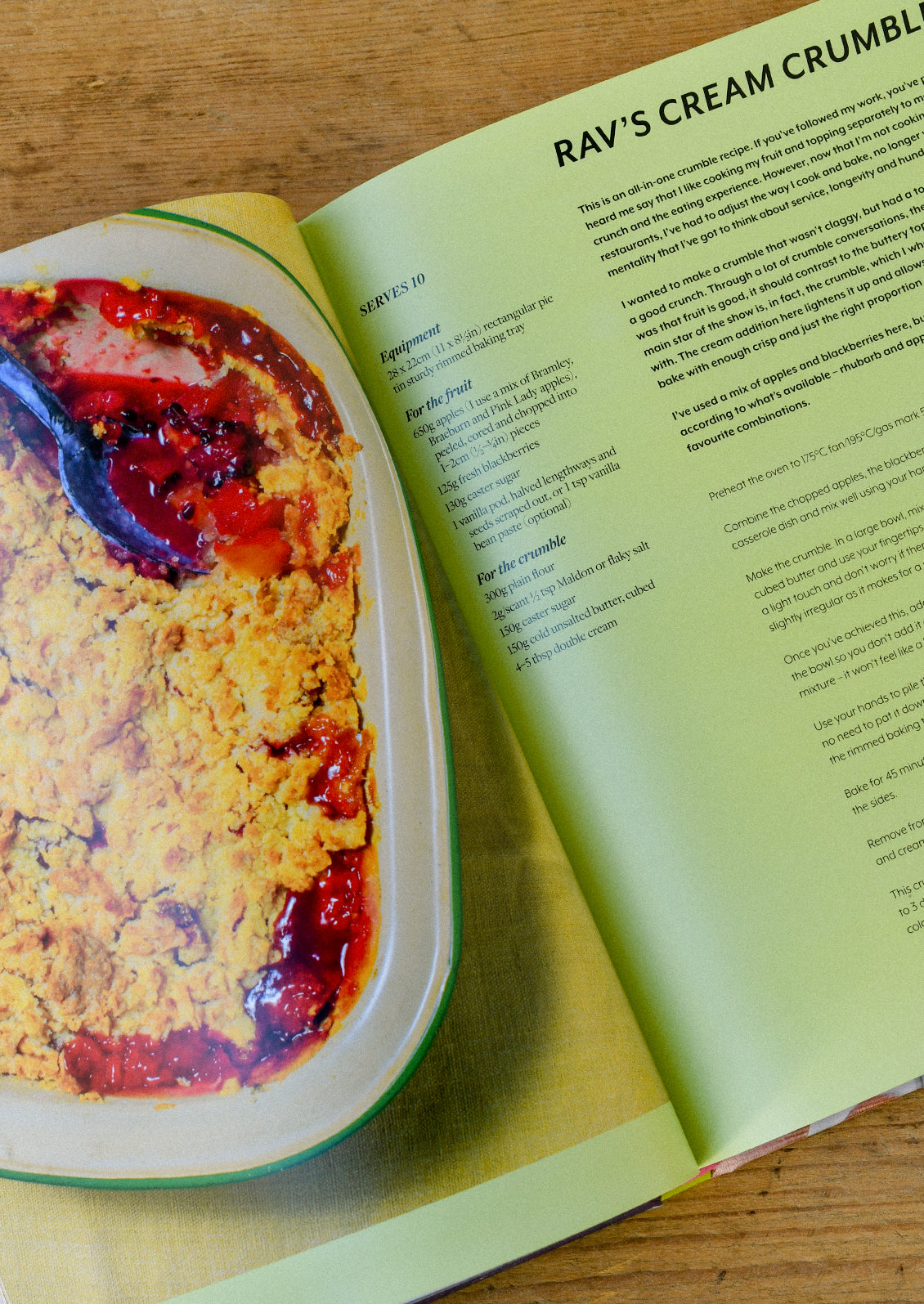 A cookbook open on a wooden table with a recipe for "Rav's Cream Crumble".