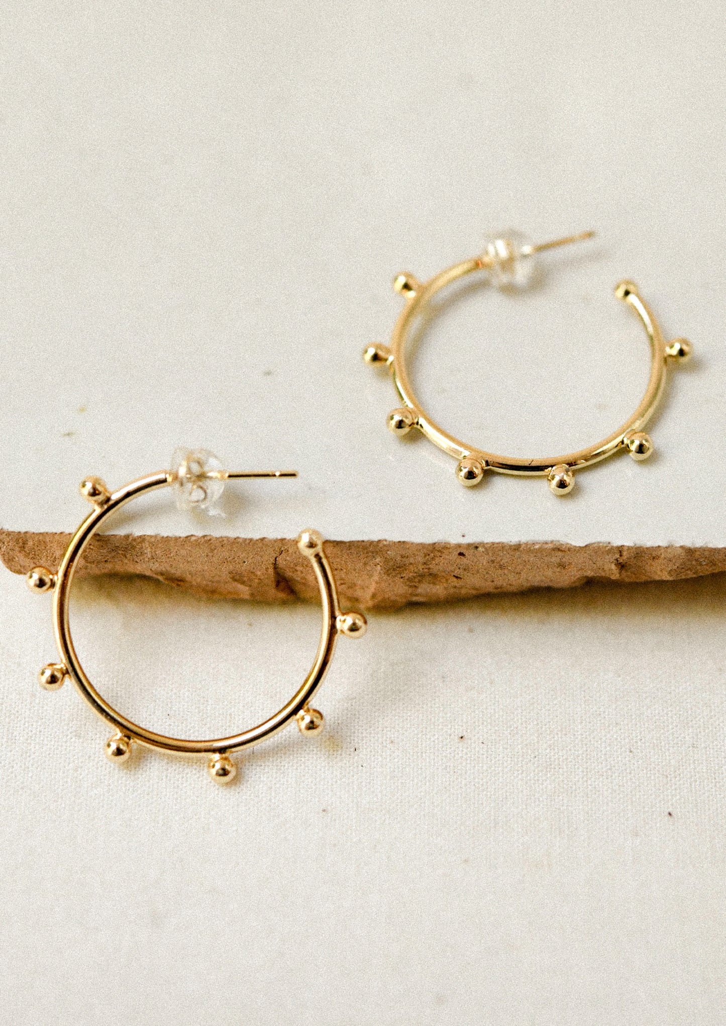 A pair of gold hoop earrings with ball details.