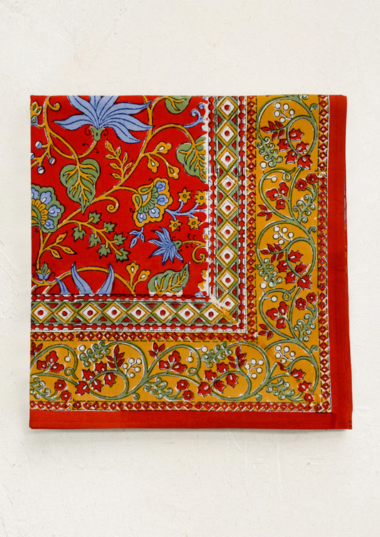 A block printed tablecloth in red with mustard, blue and green floral print.