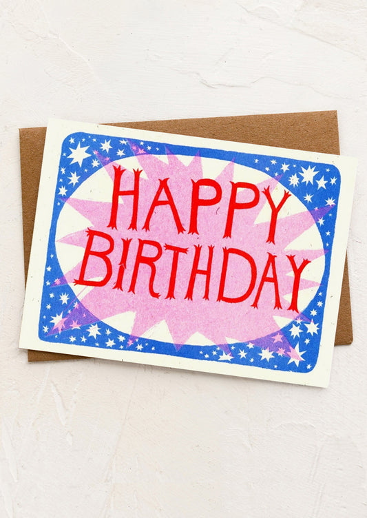 A greeting card with pink starburst and red birthday lettering.