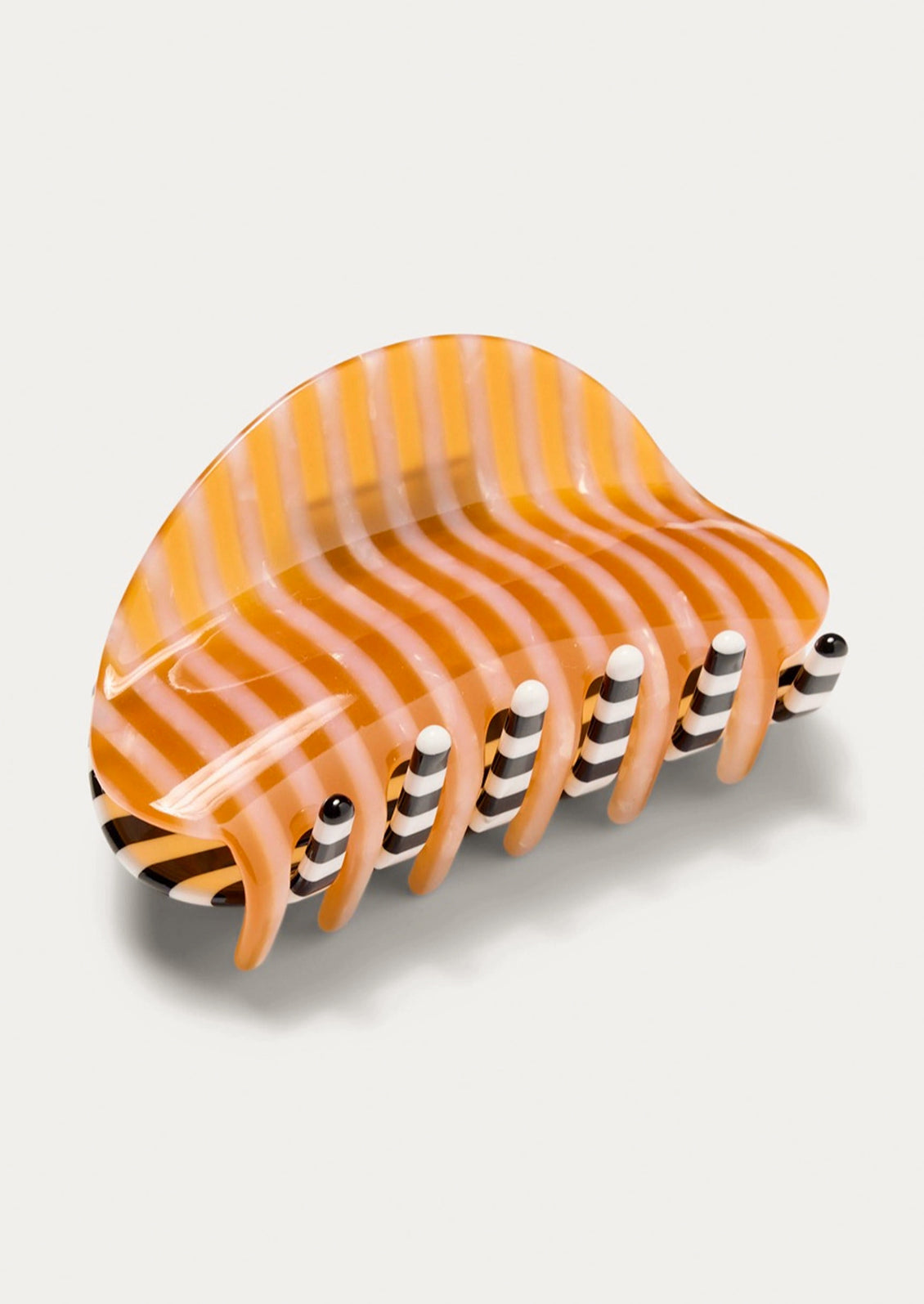 A two-tone hair claw with an orange striped pattern on one side and a black and white striped pattern on the other side.