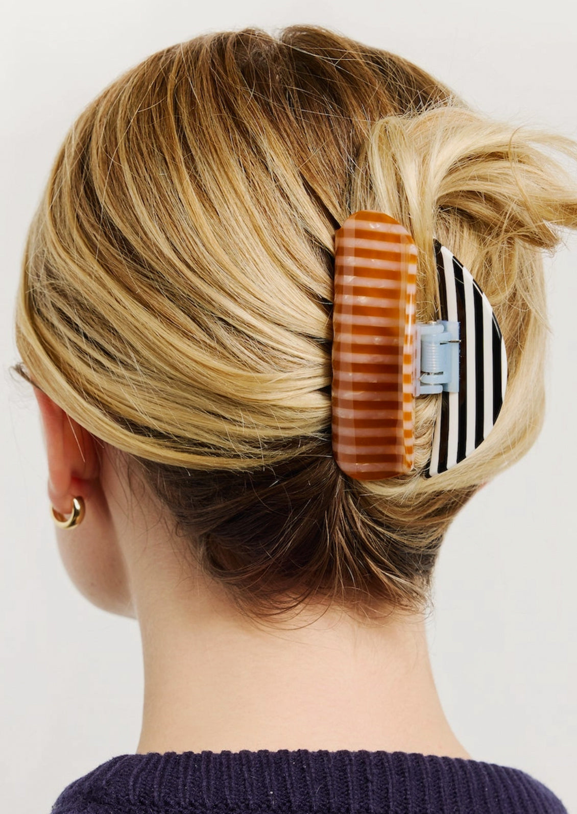 A woman wearing a hair claw with orange, white, and black stripes.