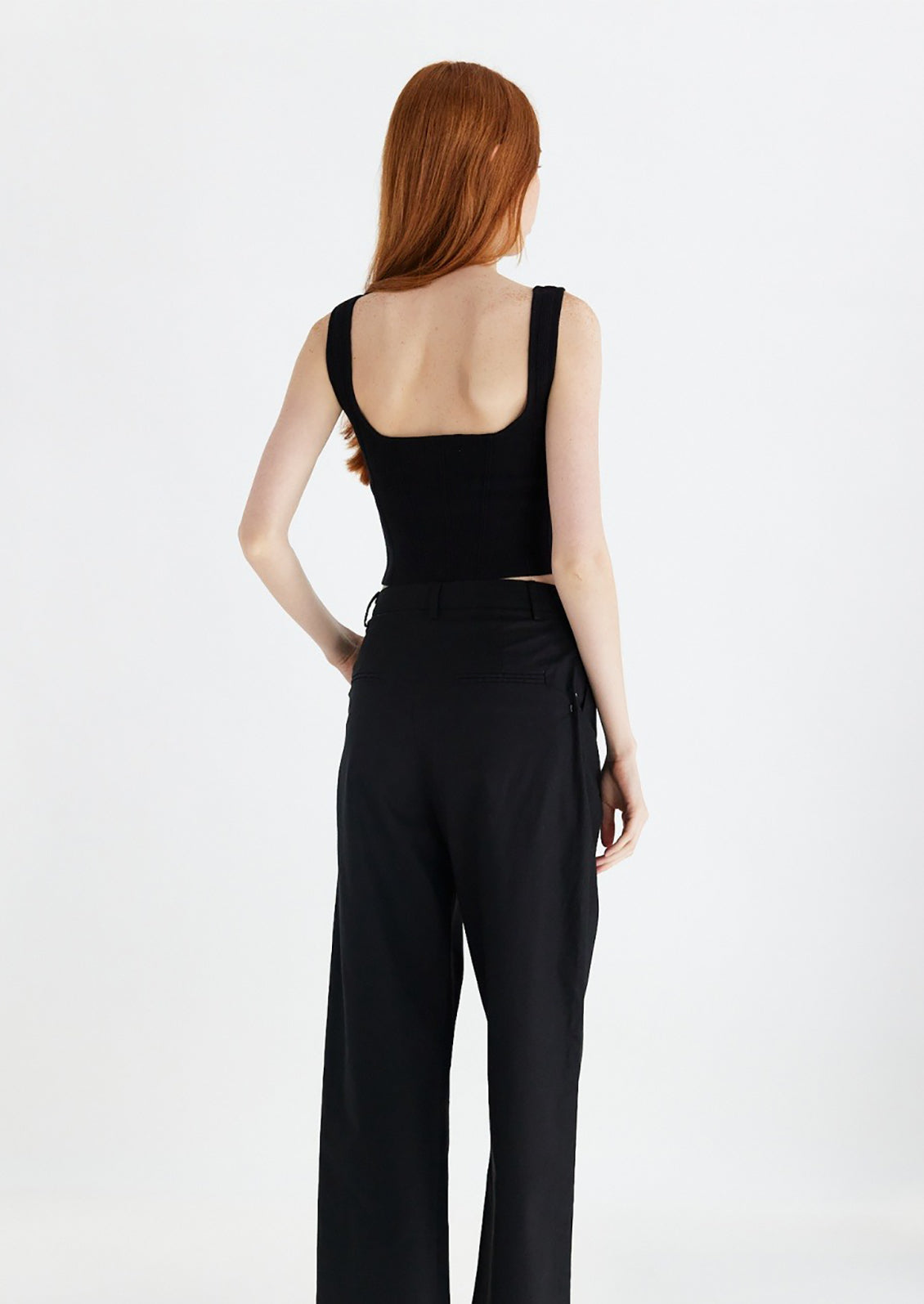 Woman wearing black knit cropped tank with low back.