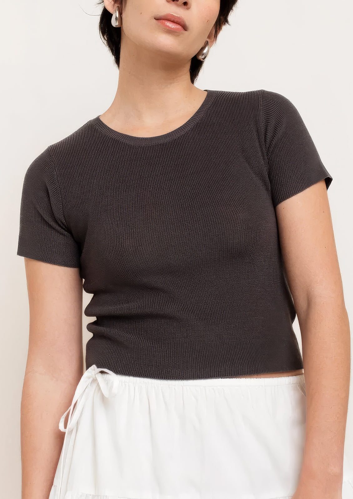 A person wearing a knit cropped t-shirt in grey.
