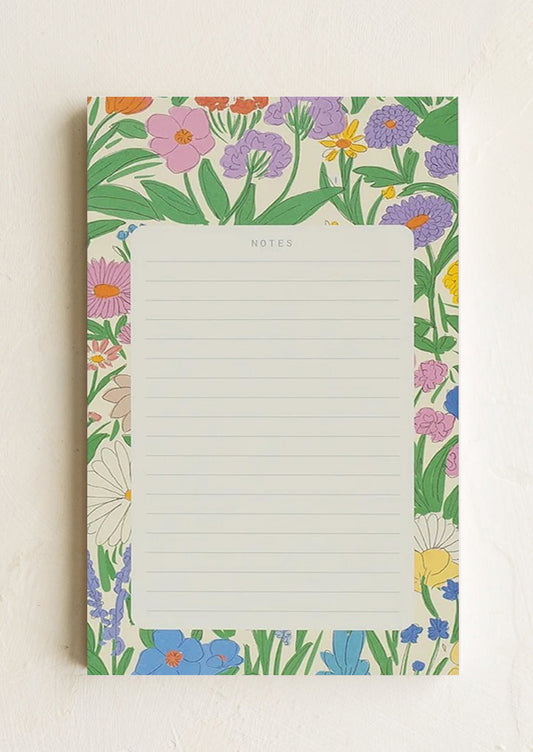 A ruled notepad with patterned background border in floral print.