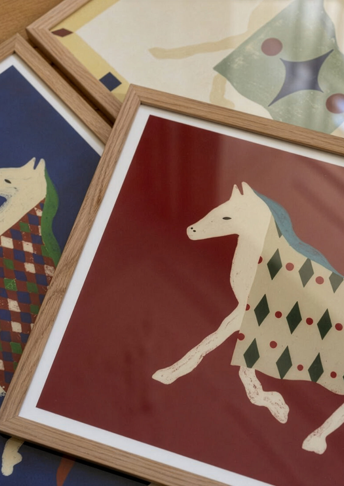 Framed illustrations of animals in colorful patterns on a wooden surface.