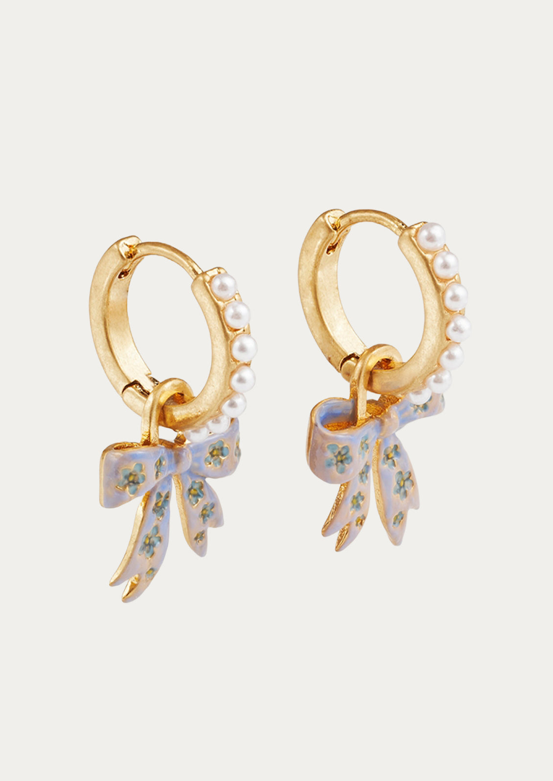 A pair of gold hoop earrings adorned with faux pearls and a bow charm.