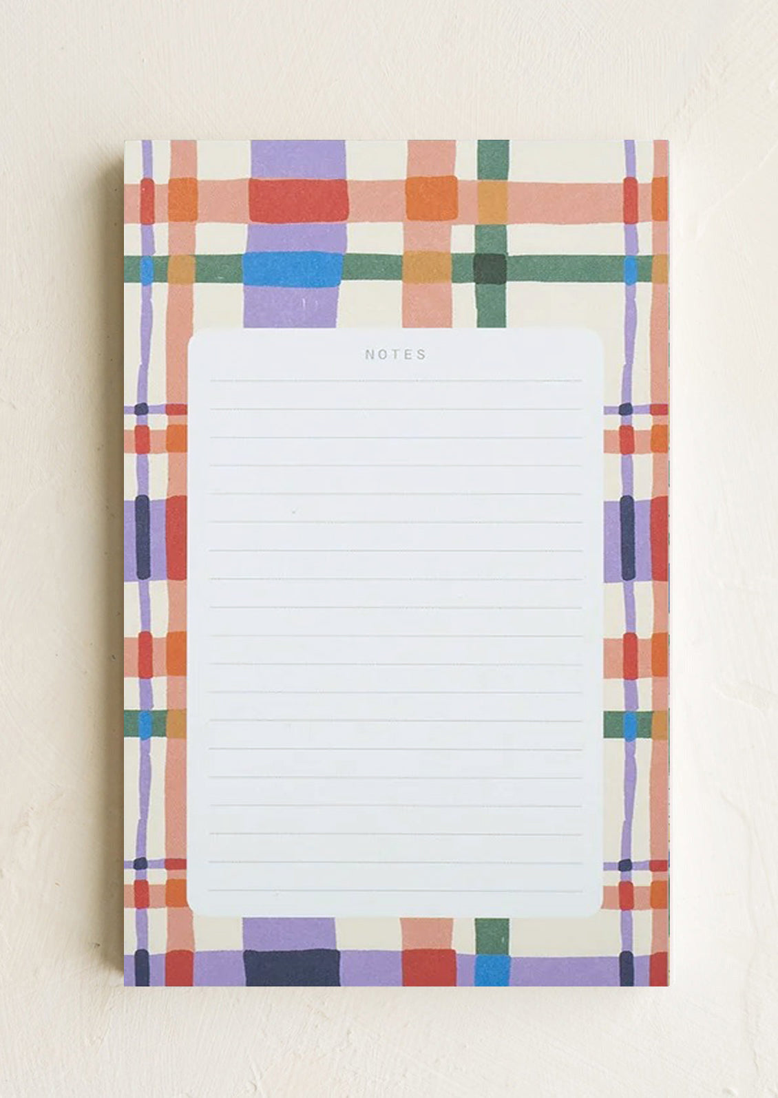 A ruled notepad with patterned background border in plaid print.