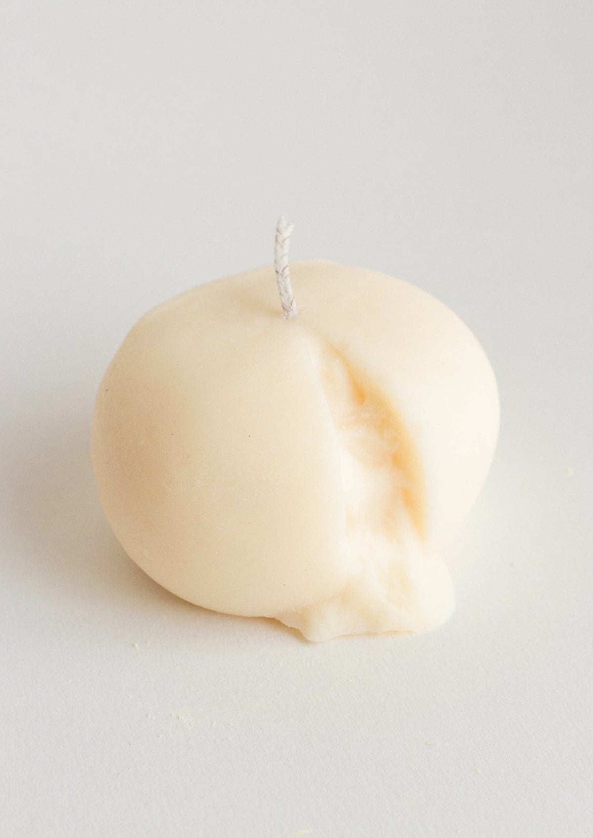 A candle in the shape of a ball of burrata cheese.