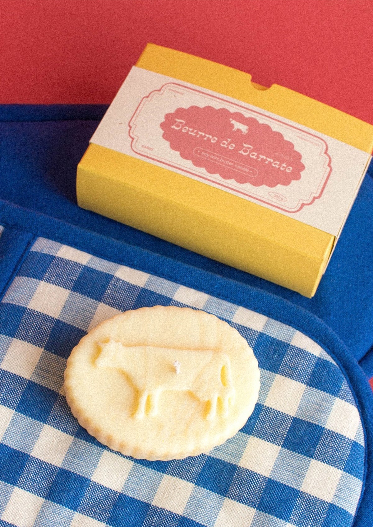 A realistic looking candle in the shape of french butter with cow shape.
