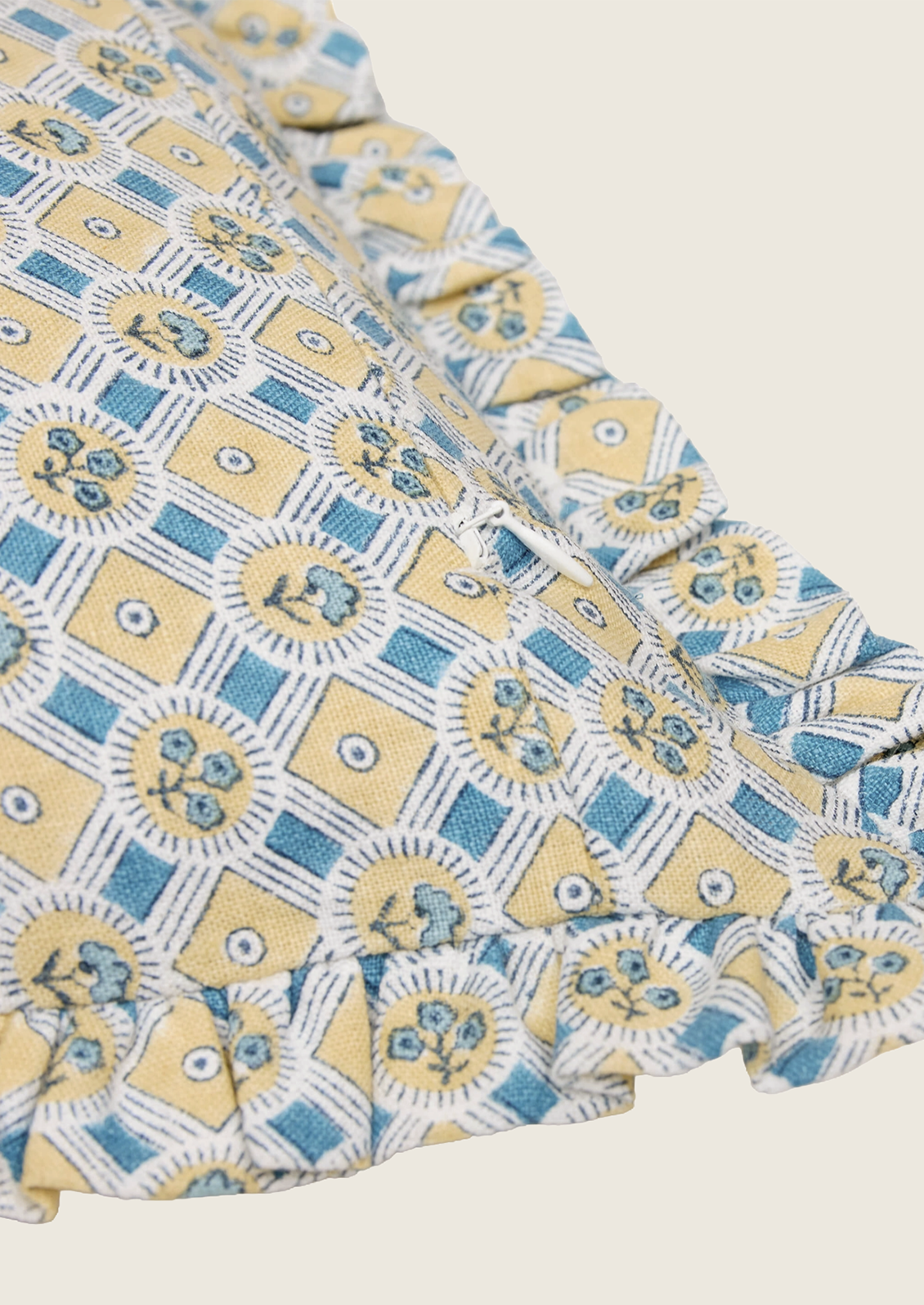 Close-up of a patterned fabric with blue and yellow design on a beige background