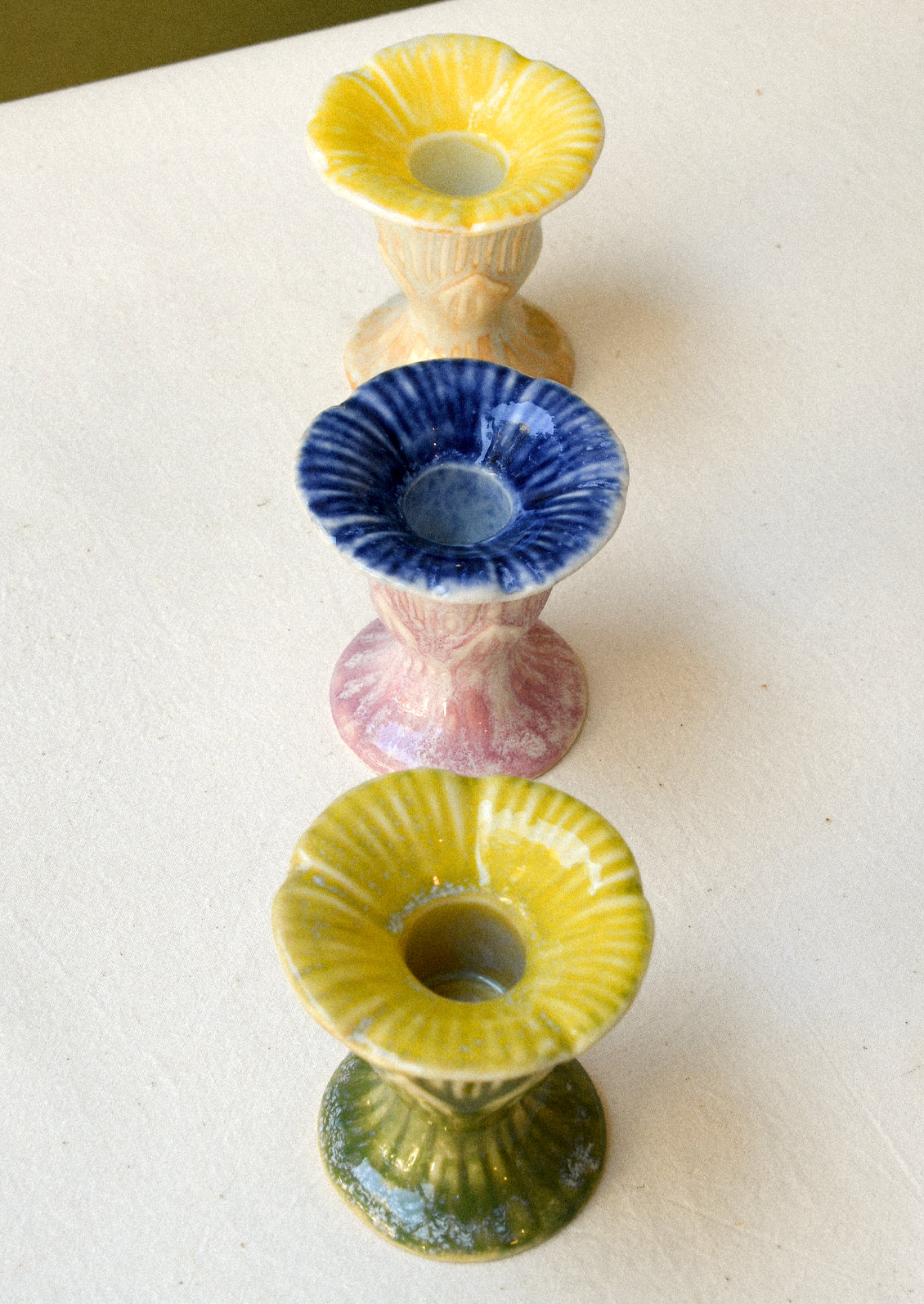 Three colorful flower-shaped ceramic taper candle holders.