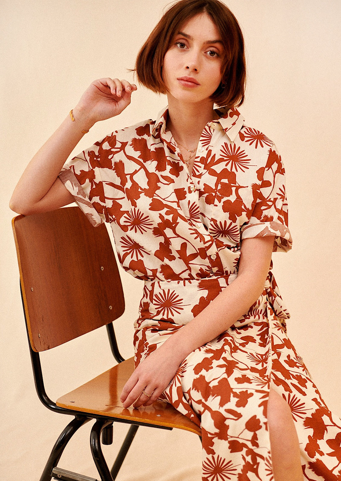 A woman wearing a short sleeve safari-style shirt in brown and white botanical print.