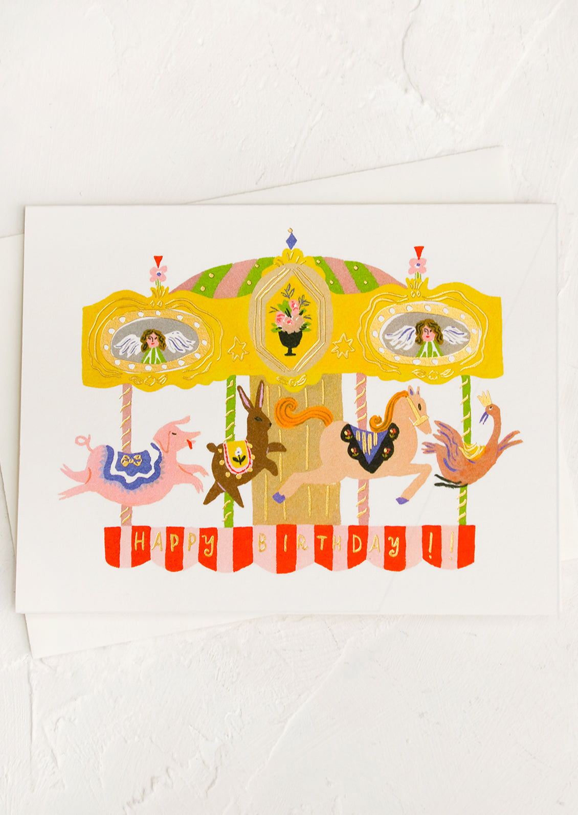 A greeting card with illustration of carousel, text reads "Happy Birthday".