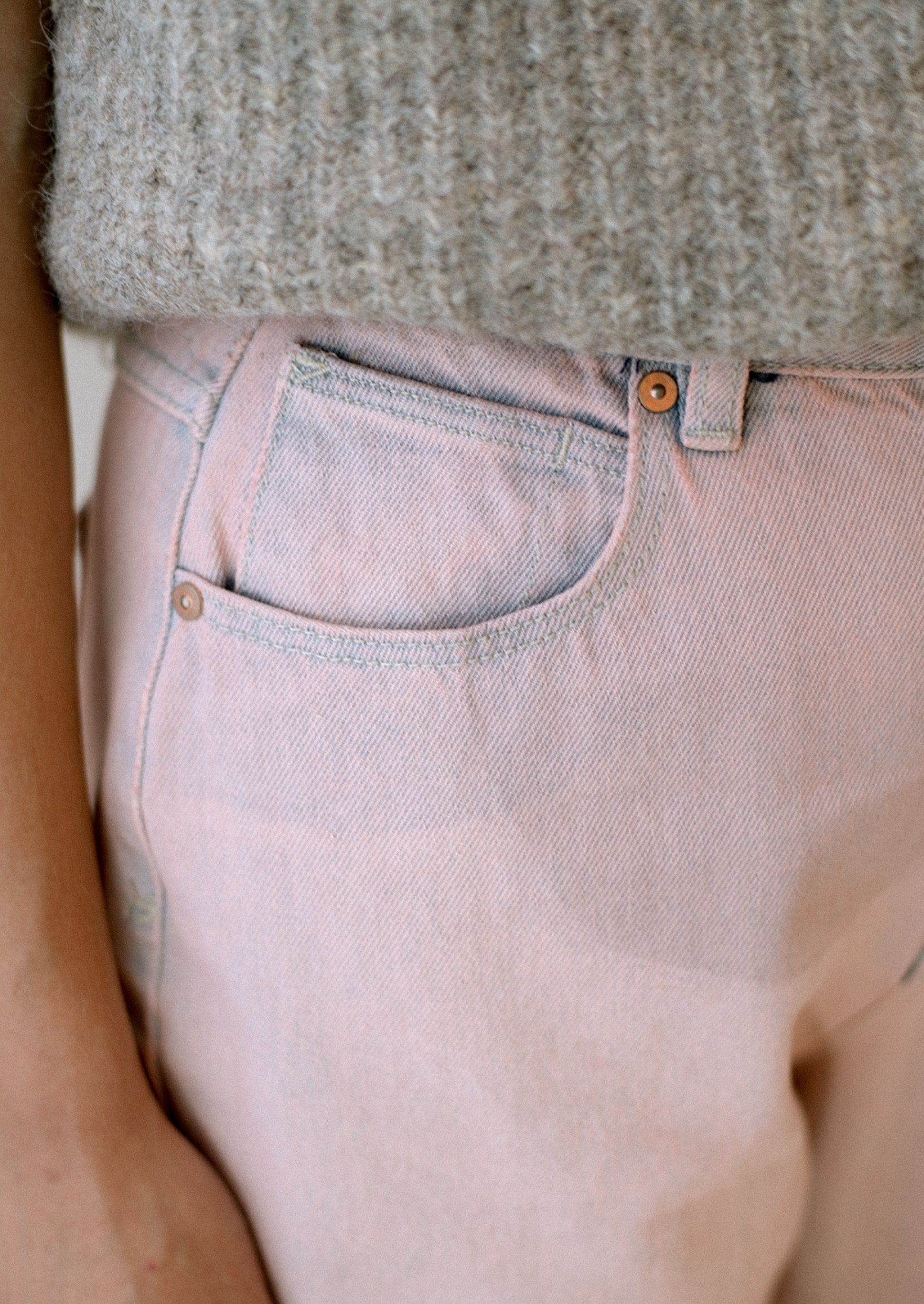 A woman wearing a pair of straight leg jeans in pink tinted wash.