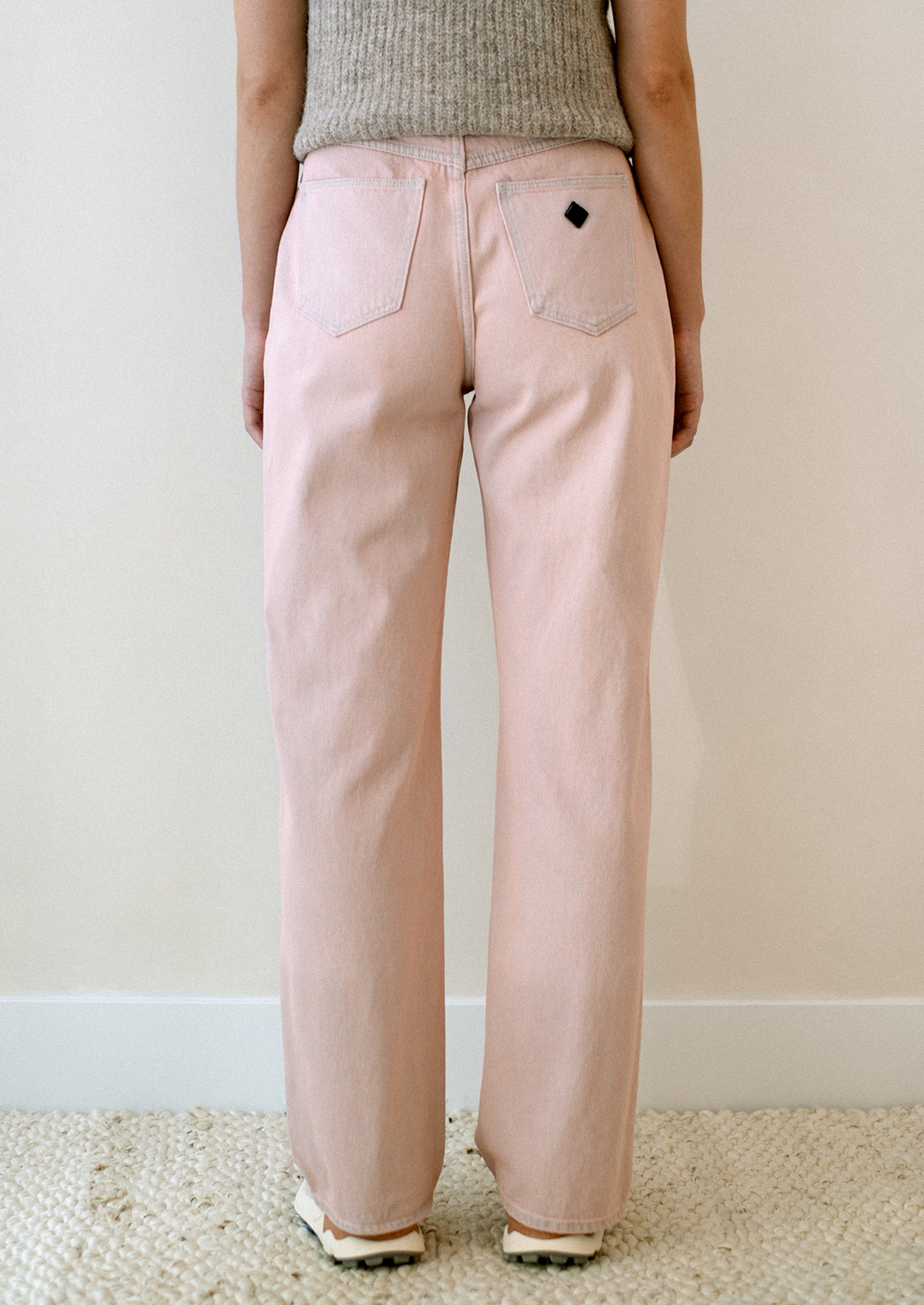 A woman wearing a pair of straight leg jeans in pink tinted wash.