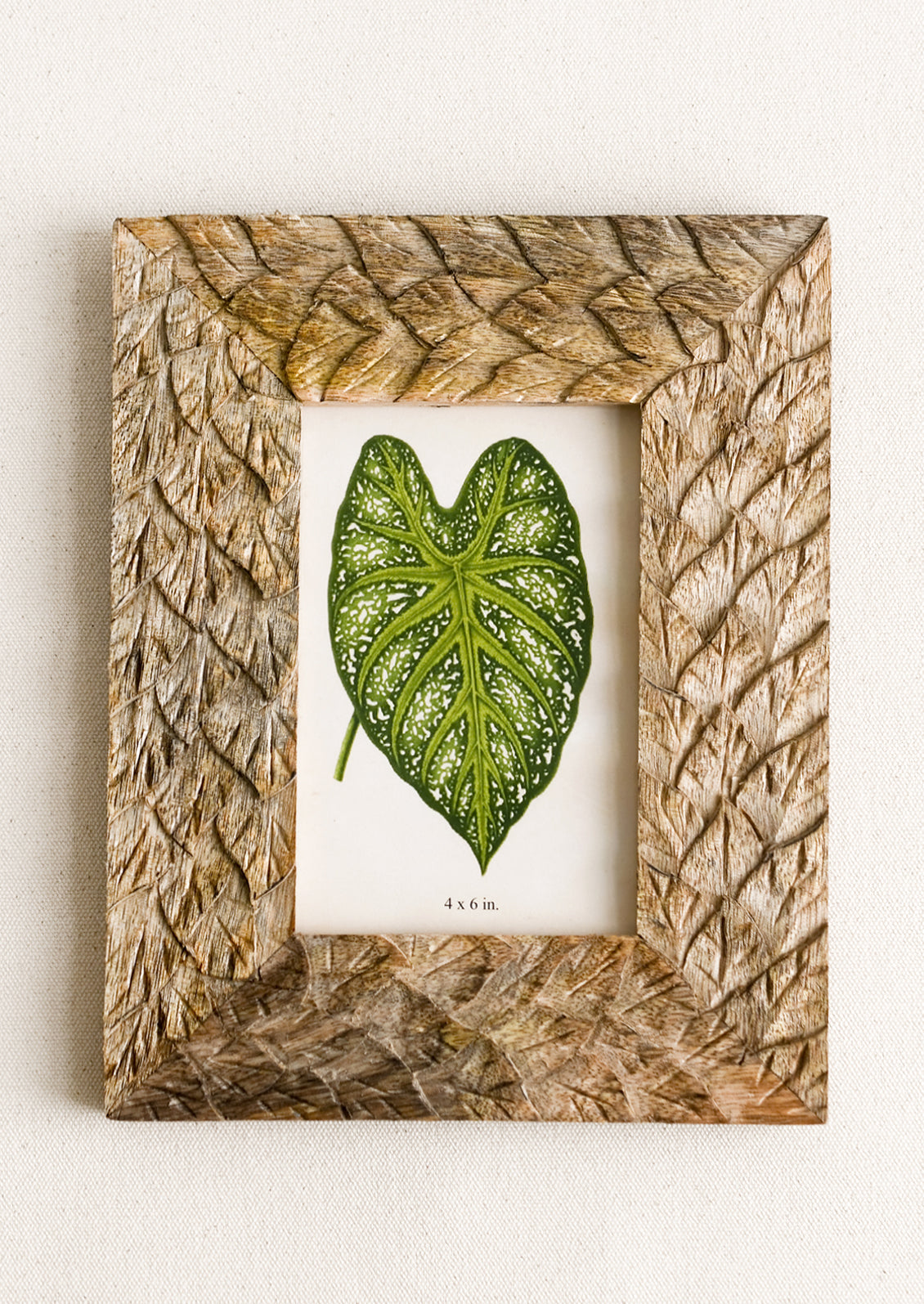 A mango wood picture frame with textural carved leaf pattern.