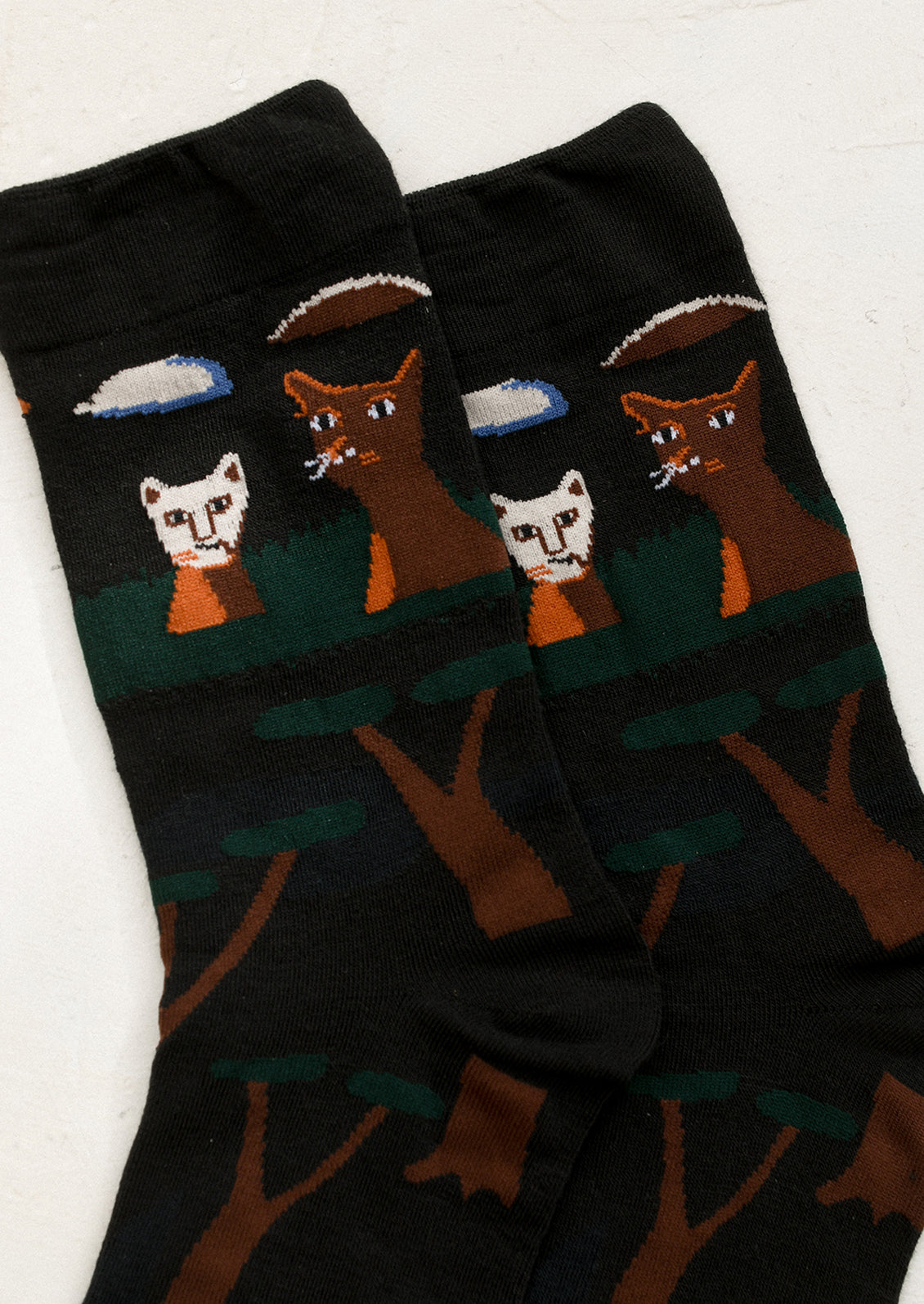 A pair of black socks with cat and tree print.
