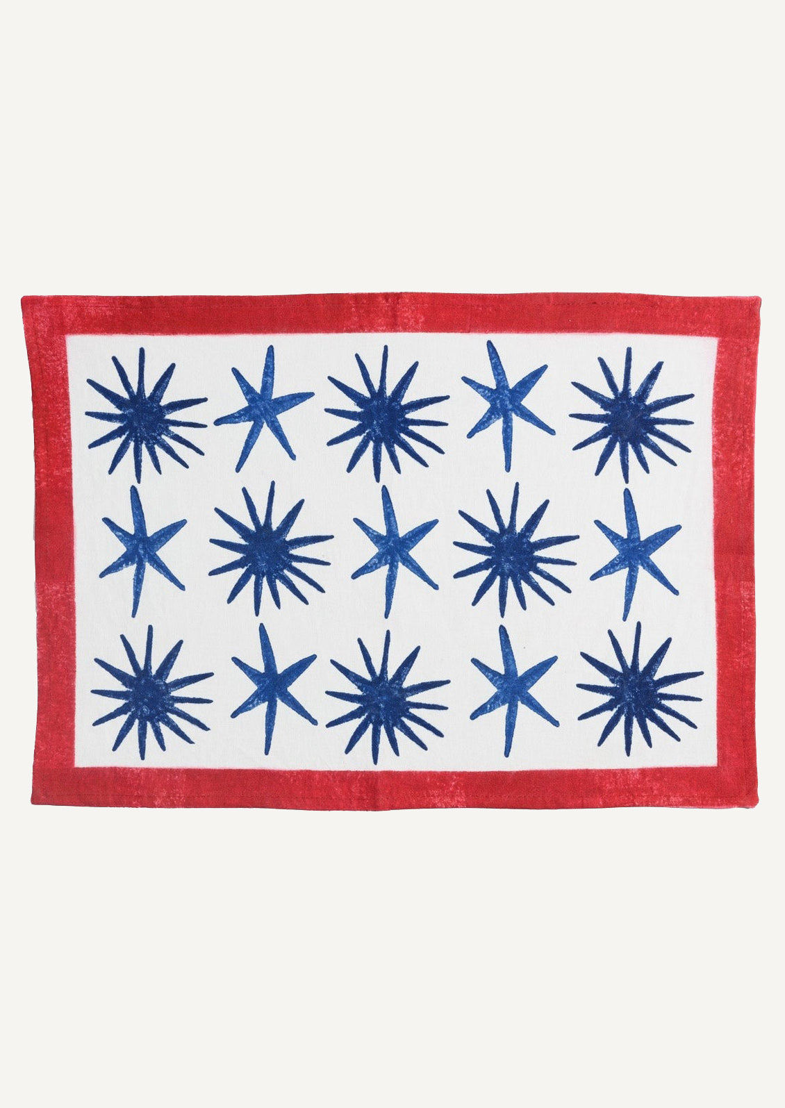 A block printed placemat in white with blue stars and red border.