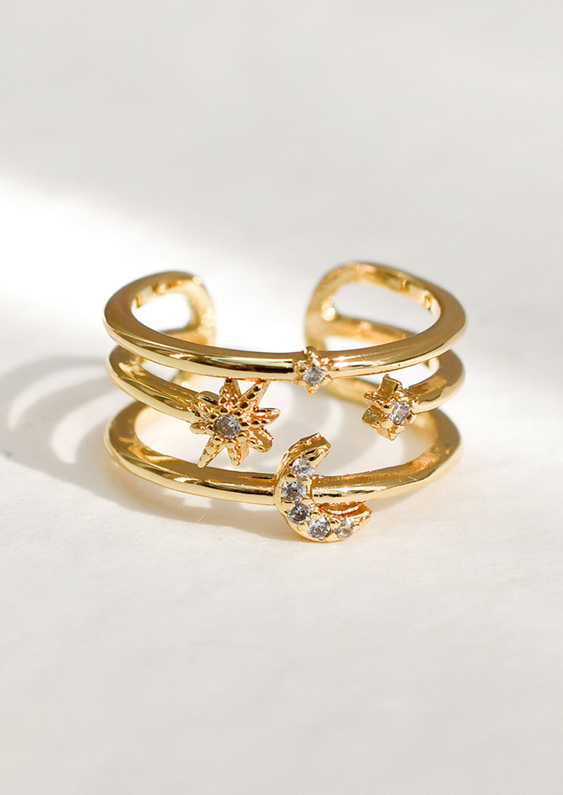 A gold triple band ring with star and moon detailing.