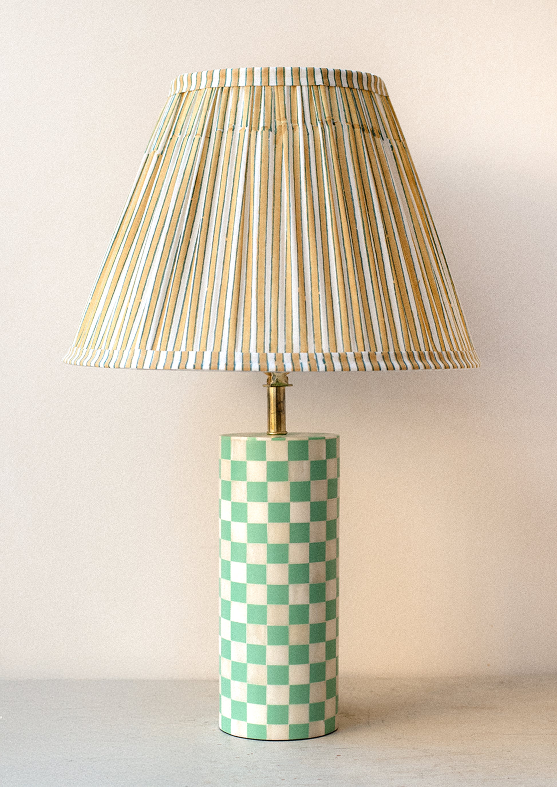 A table lamp with mint and cream checker print cylinder base with stripe printed pleated lampshade.