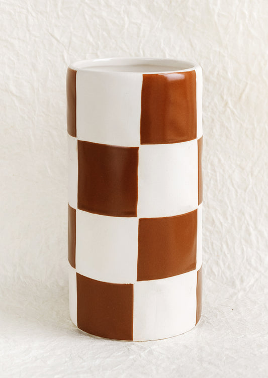 A tall cylindrical ceramic vase in white with brown checker pattern.