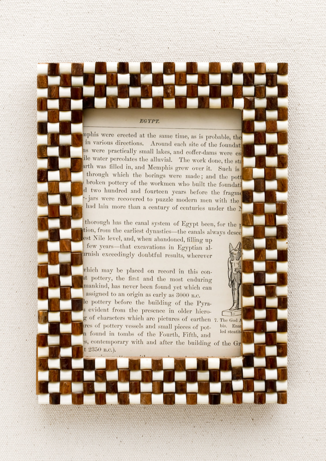 A picture frame with textural raised brown and white checker weave pattern.