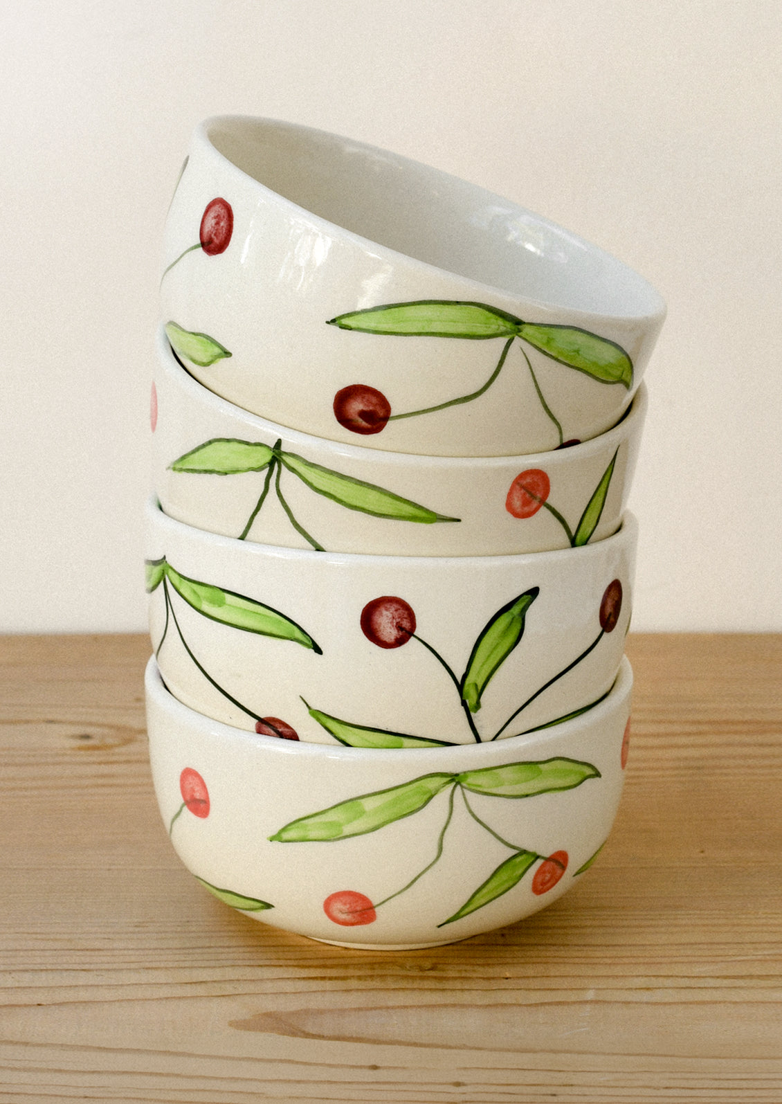 A stack of ceramic bowl with a hand drawn illustration of cherries.