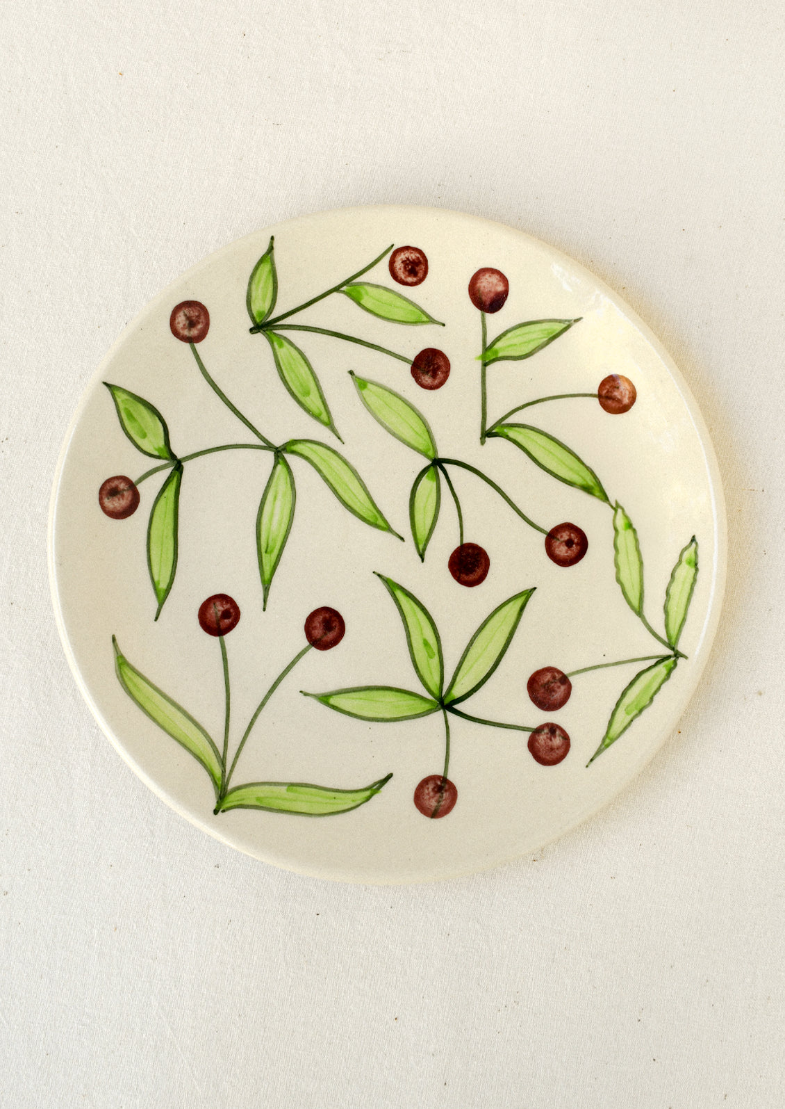 A ceramic plate with illustrated dark cherries.