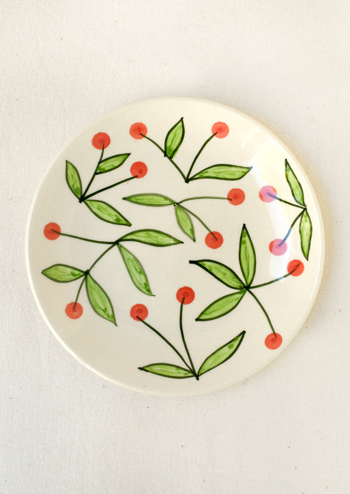 A ceramic plate with illustrated red cherries.
