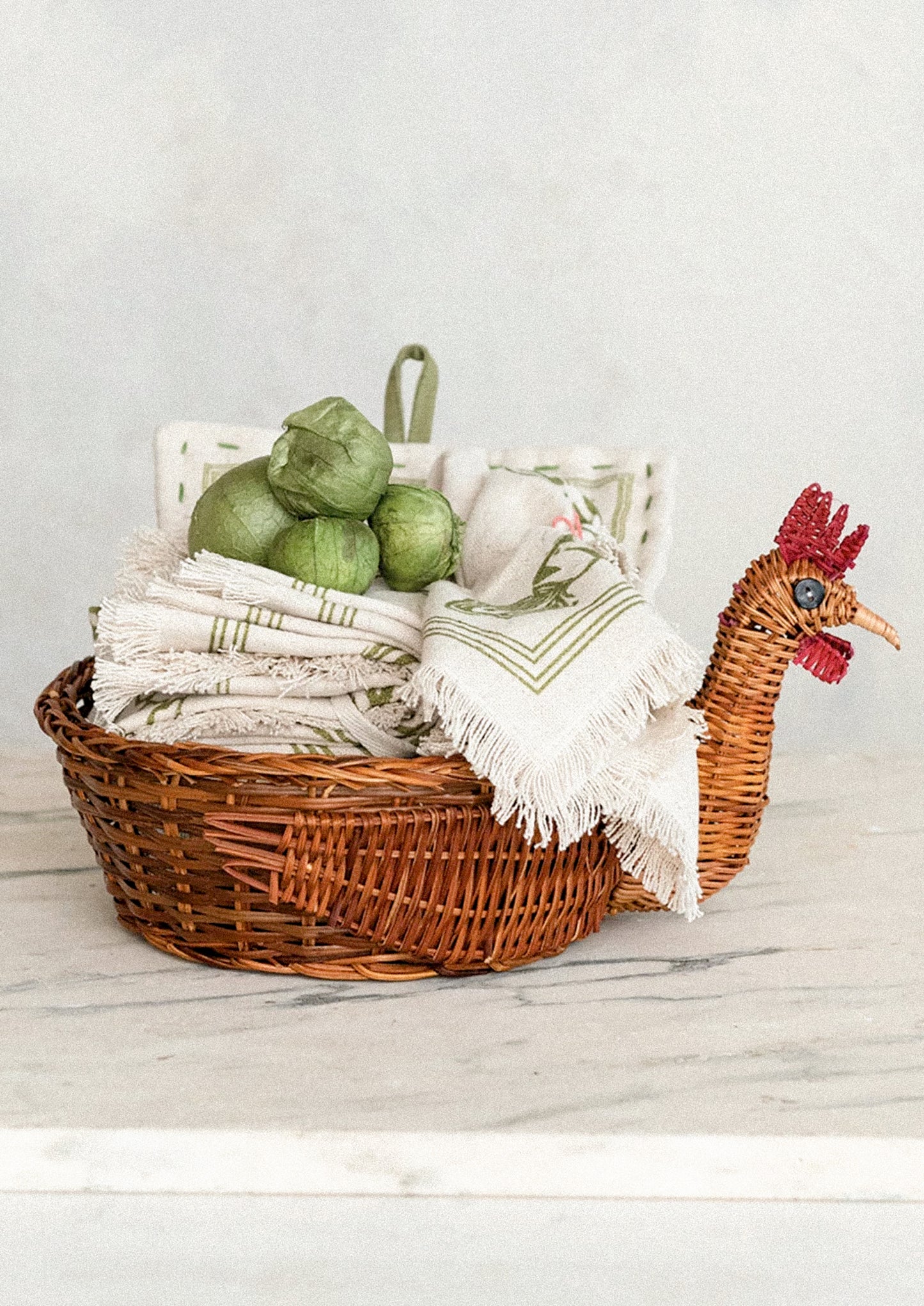 A woven basket with three dimensional chicken head detailing on side.