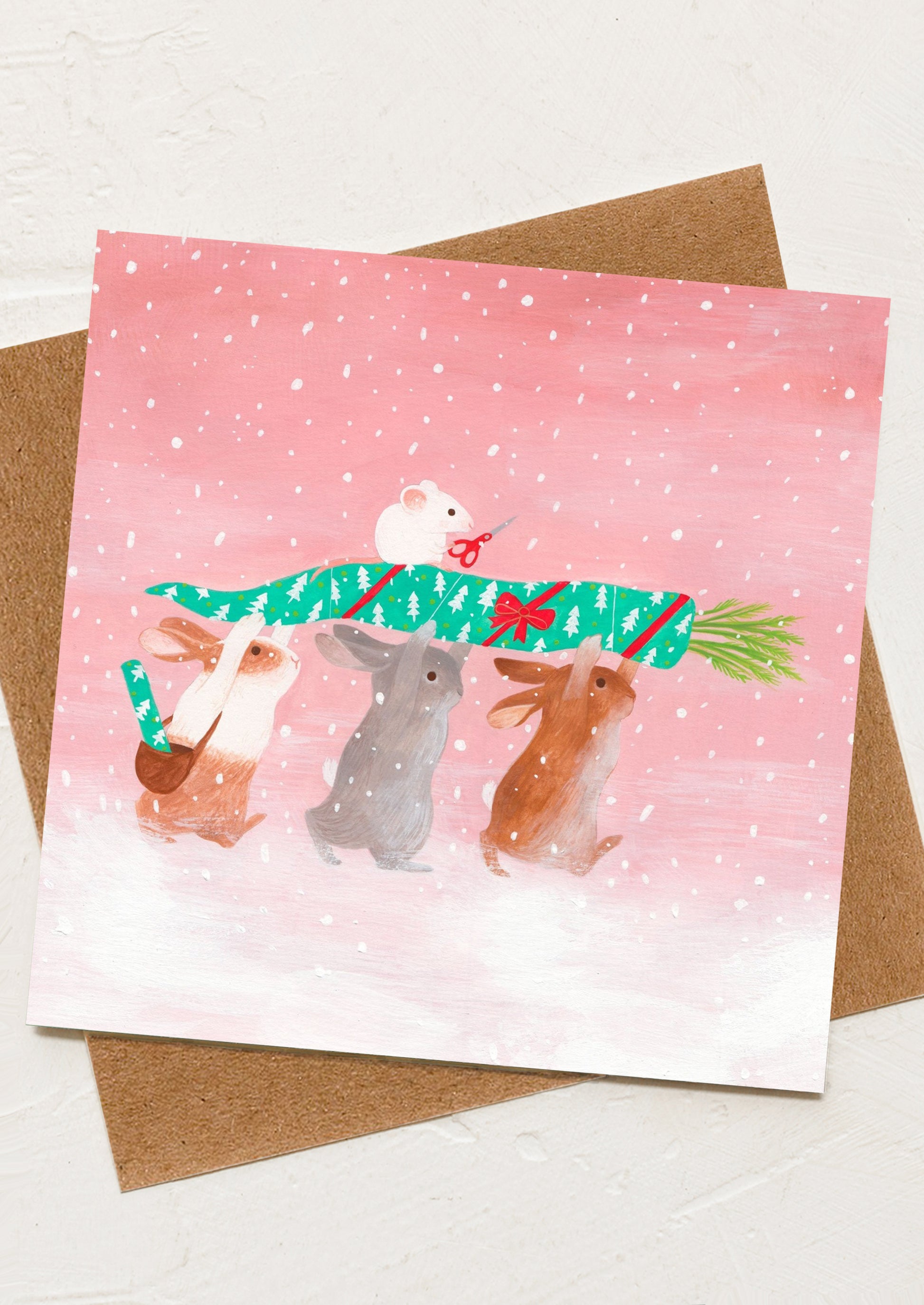 A greeting card with image of bunnies holding a gift wrapped carrot.