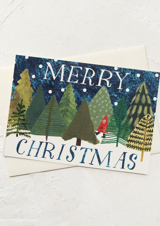 A greeting card with illustration of a red figure amidst a forest of trees and snowy sky.