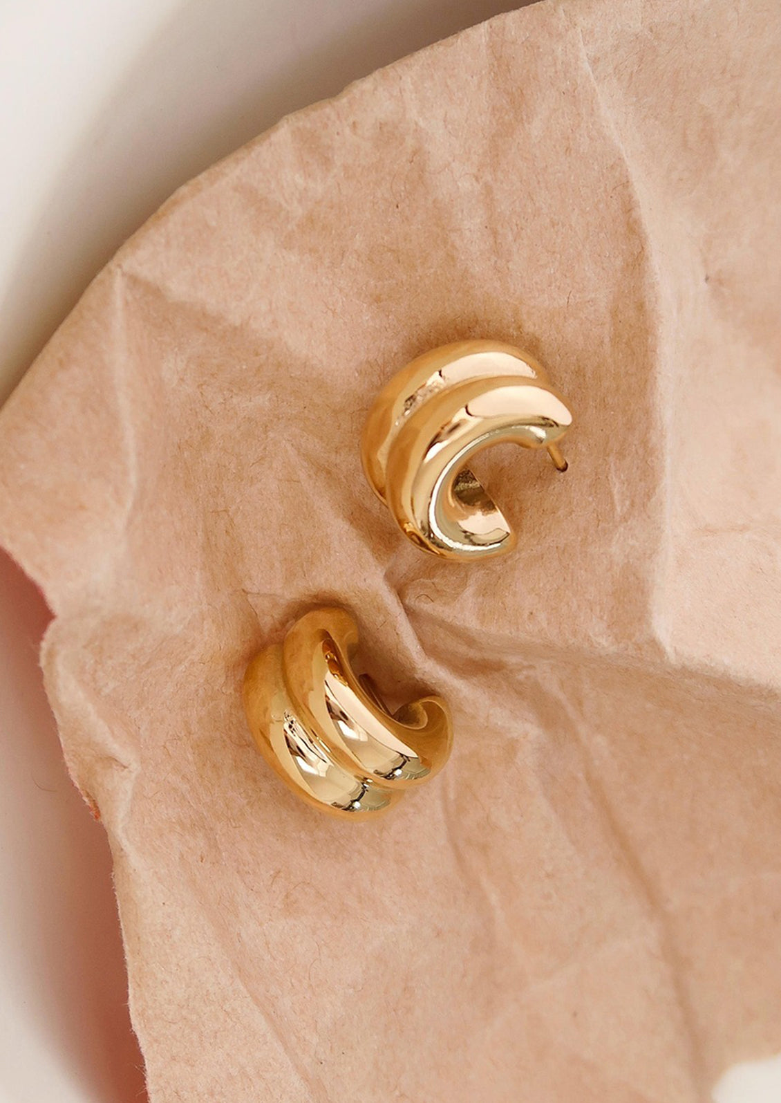 A pair of chunky rib textured hoop earrings in gold.