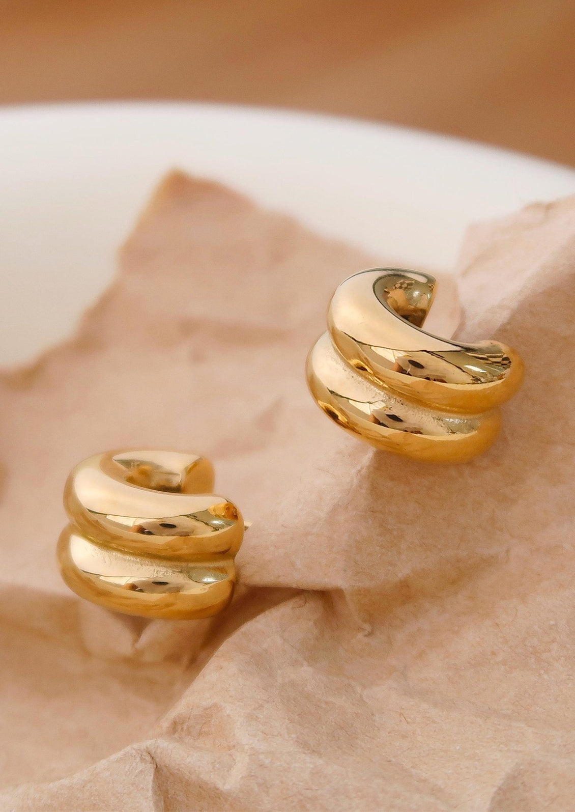 A pair of chunky rib textured hoop earrings in gold.