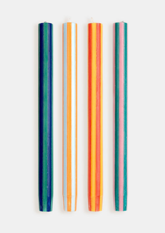 A set of striped taper candles in bright orange, yellow, pink, and green colors.