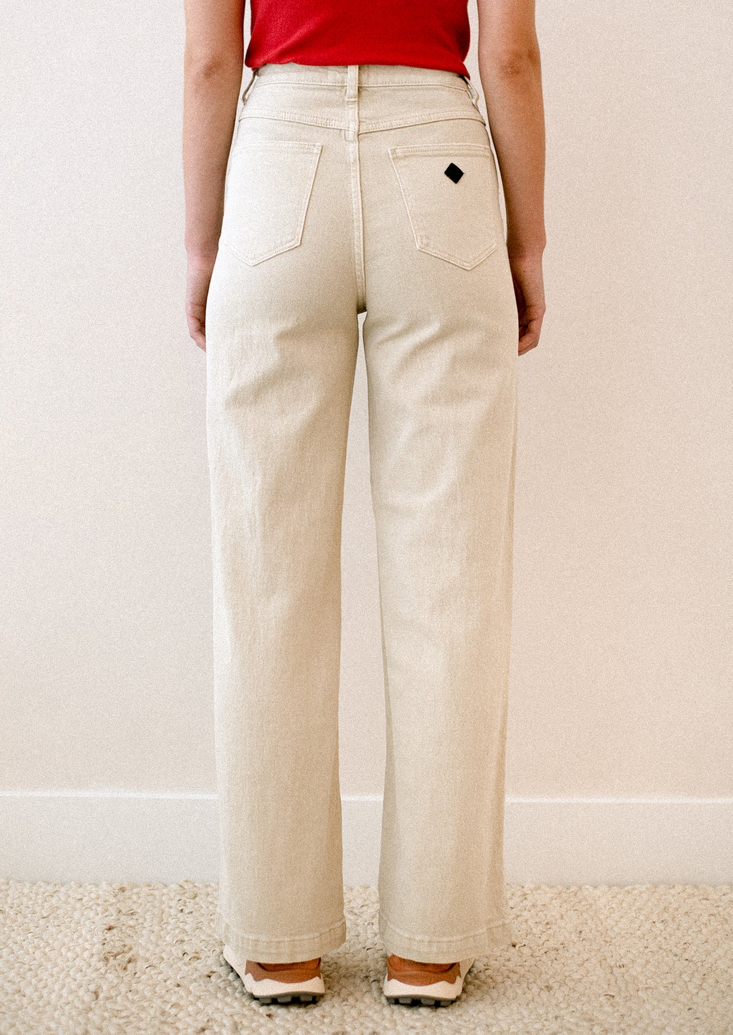 A woman wearing a pair of cream colored jeans with high rise and wide leg.
