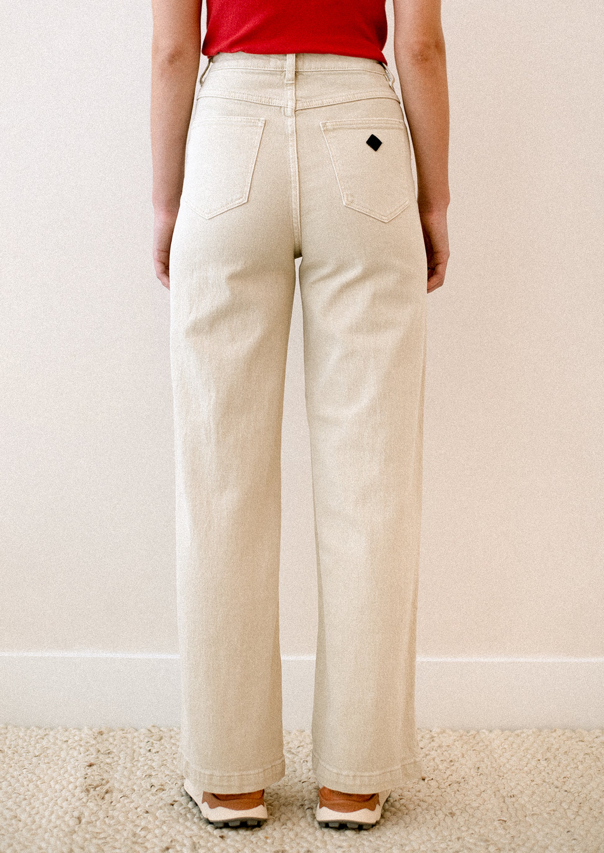 A woman wearing a pair of cream colored jeans with high rise and wide leg.