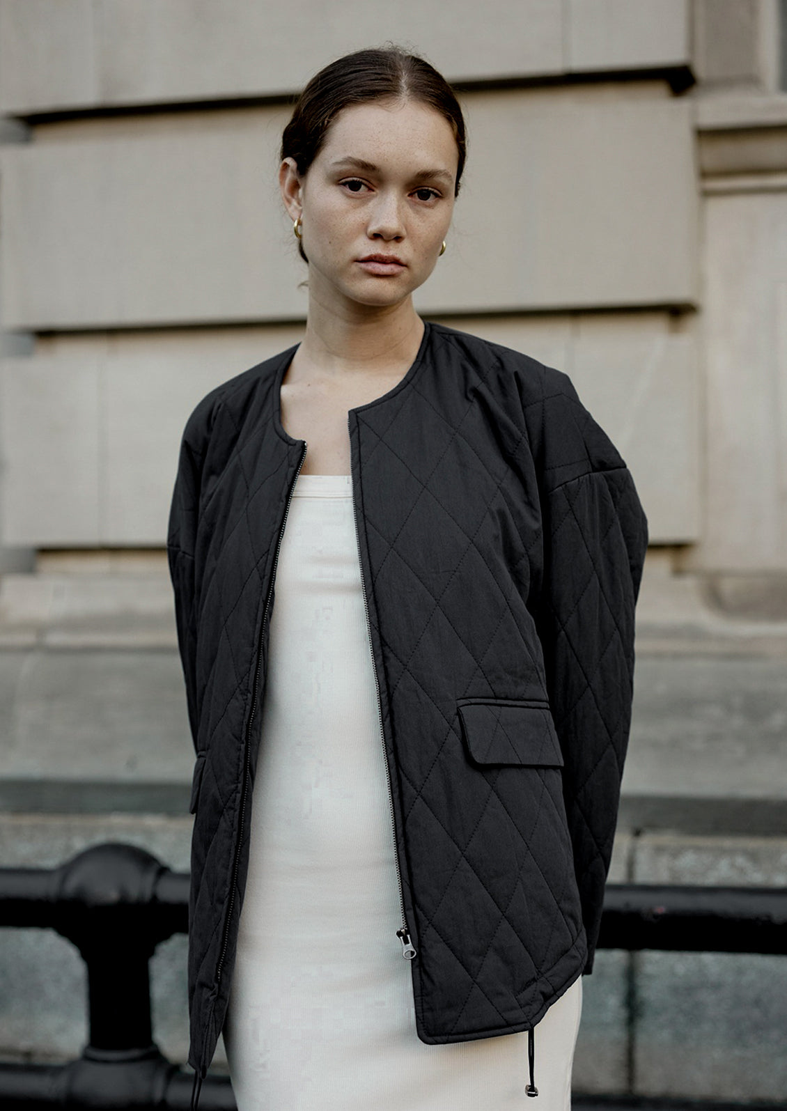 A woman wearing a padded quilted jacket with bottom drawstring detail in black.