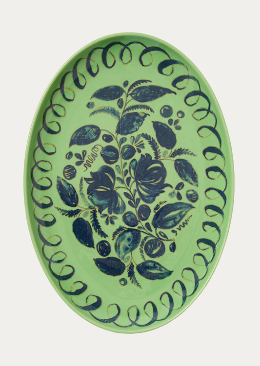 Decorative plate with blue floral pattern on a green background
