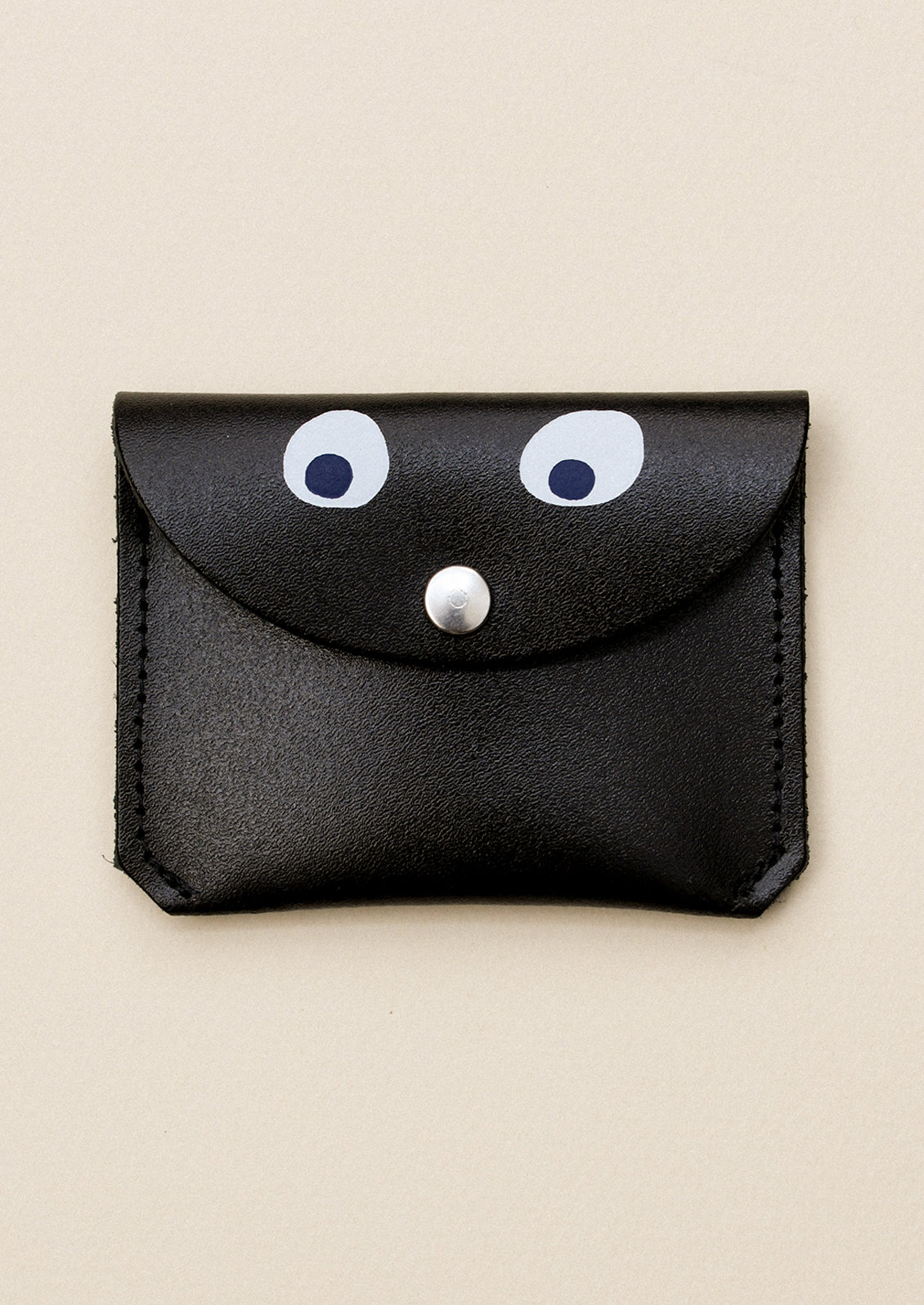 A black leather flap front coin pouch with hand painted googly eye detail.