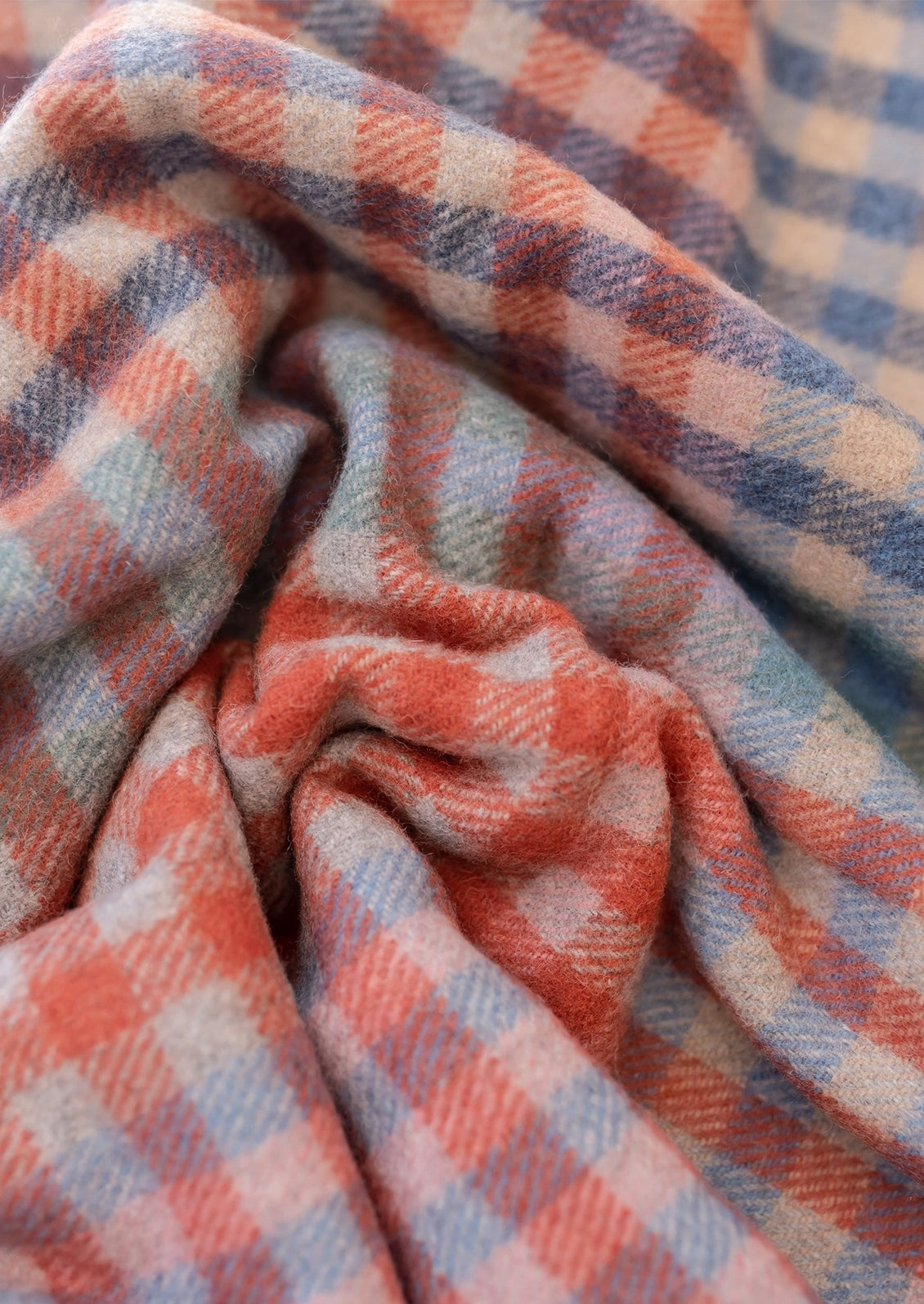 A gingham check patterned wool blanket in shades of red and cornflower blue.