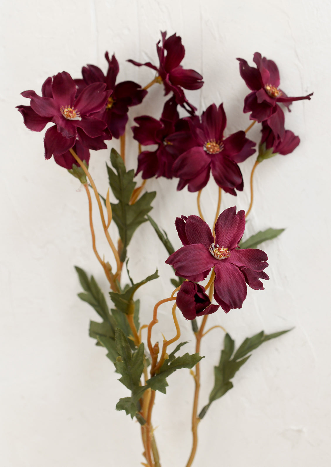 A faux floral spray depicting cosmos flowers in merlot.
